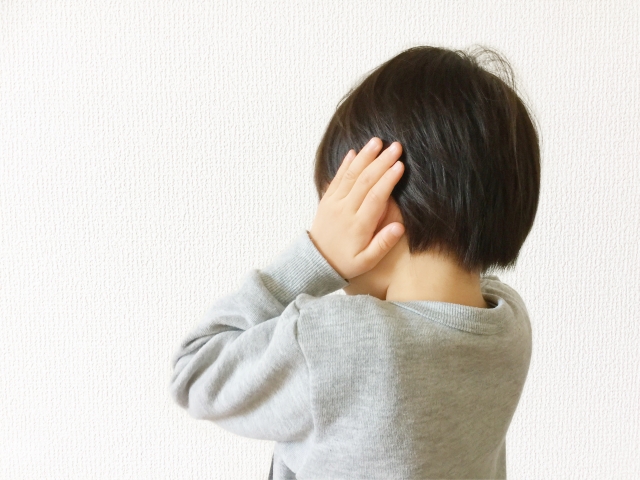 耳を両手で押さえる男の子