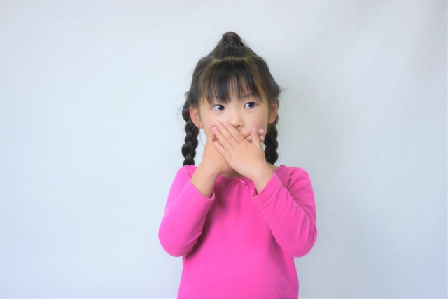 口を塞いでいる女の子