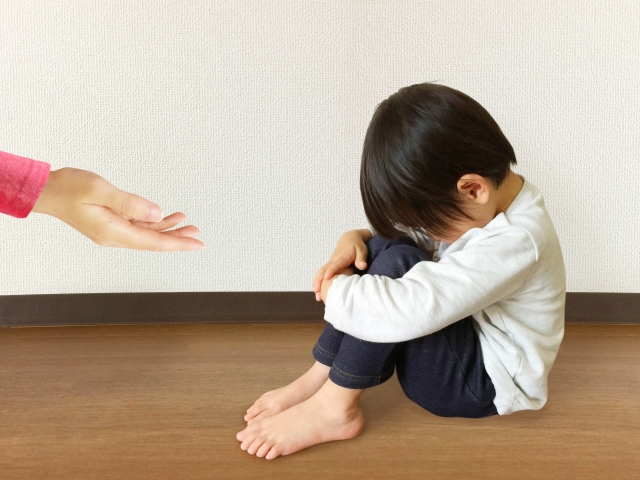 落ち込んでいる子供に手招きする大人