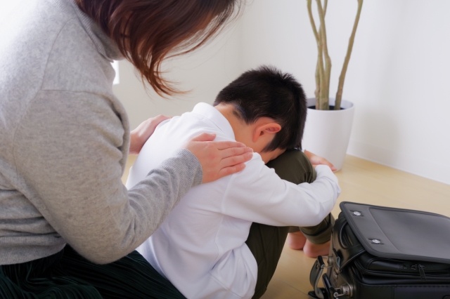 落ち込んでいる男の子を慰める母親