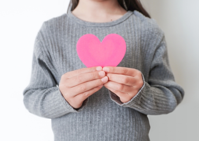 ハートの紙を胸に当てる女の子