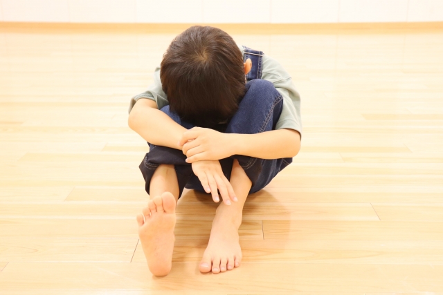 床に顔を伏せながら座っている男の子