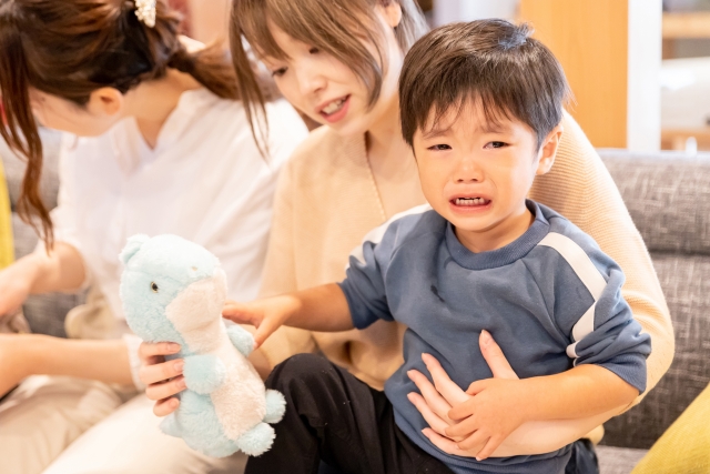 泣いている男の子をおもちゃであやすお母さん