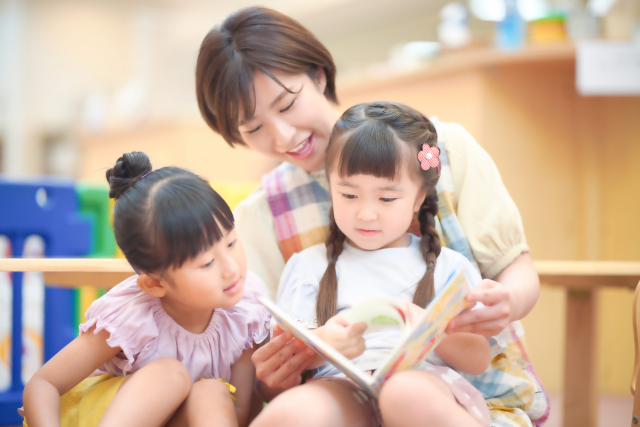 女の子に本を読み聞かせる優しそうな先生