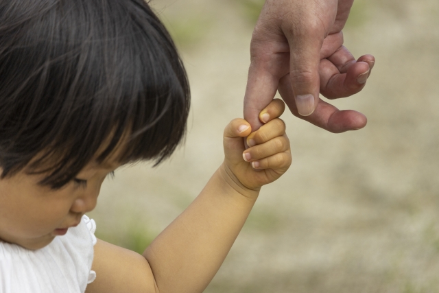 大人の指を握る小さな子供