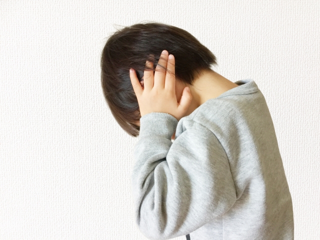 耳を塞いで下を見る男の子