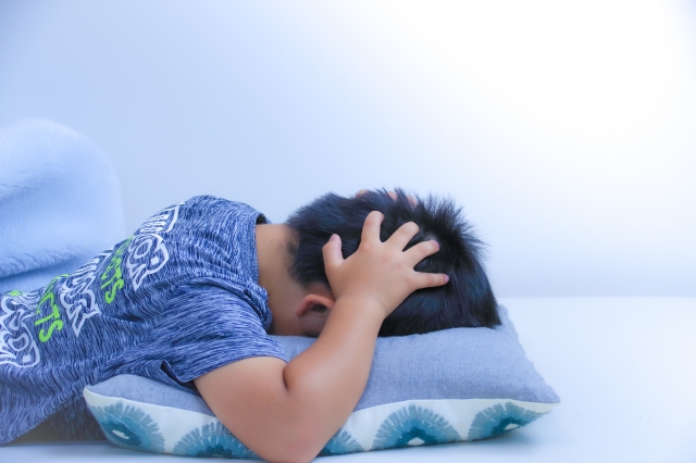 枕の上で頭を抱える男の子