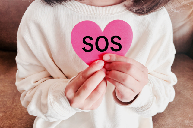 SOSと書かれた紙をもっている女性