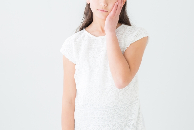 頬を抑える女のこ