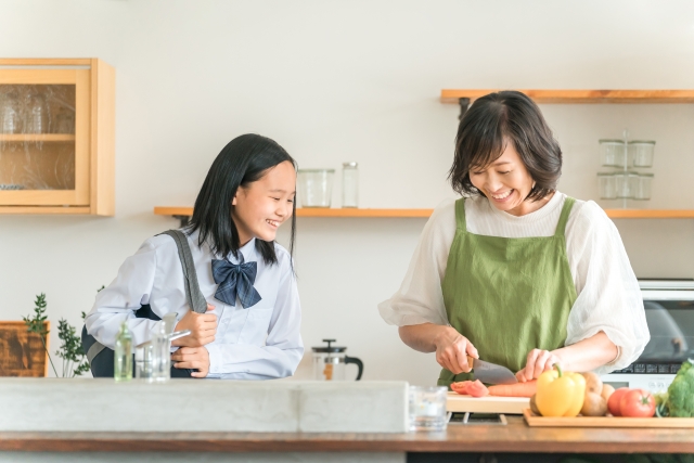 キッチンで笑顔で話をしてるお母さんと女子学生