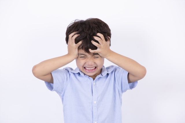 頭をかかえイライラしている様子の男の子