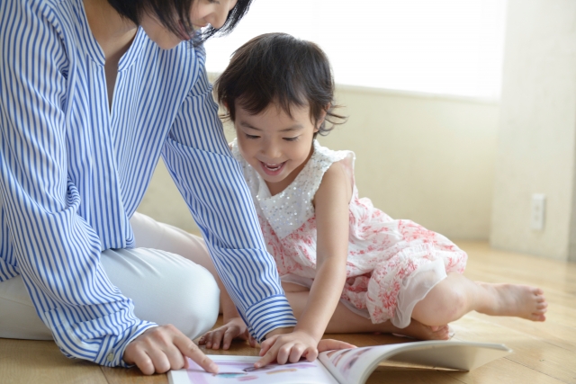 ママと楽しそうに絵本を見ている女のこ