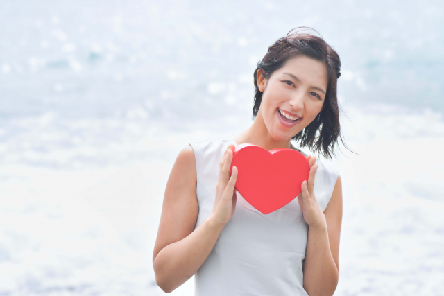 ハートを持って笑顔の女性