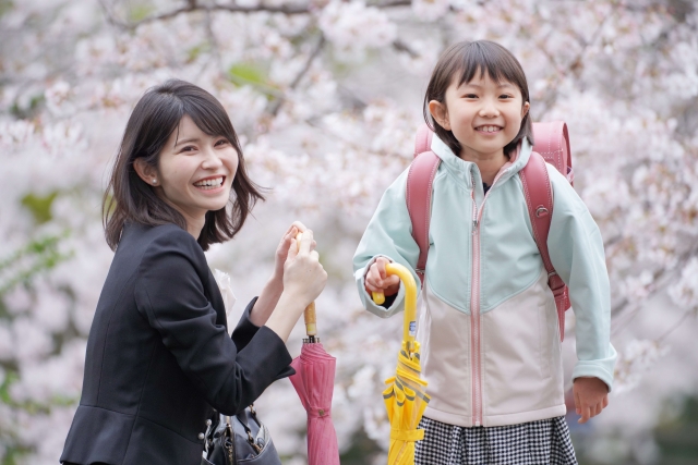 桜の前で写真を撮る親子