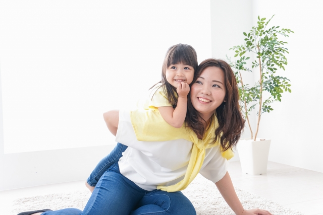 お母さんの背中の上に楽しそうに乗っている女の子