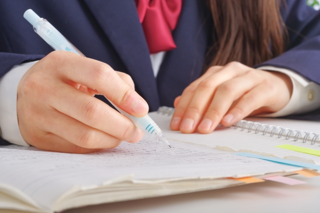ノートに文字を書いている女子学生