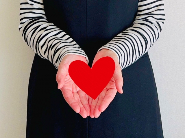 両手でハートを持つ女性