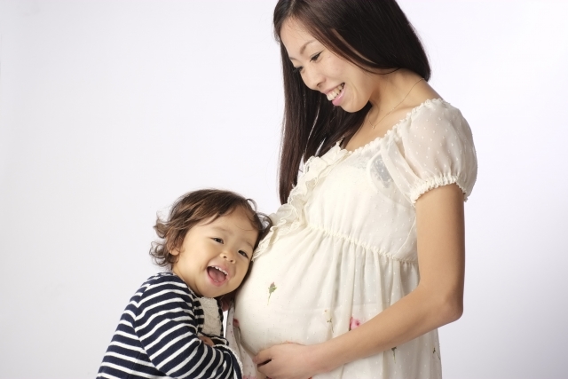 妊婦のお腹に顔を近づける子供