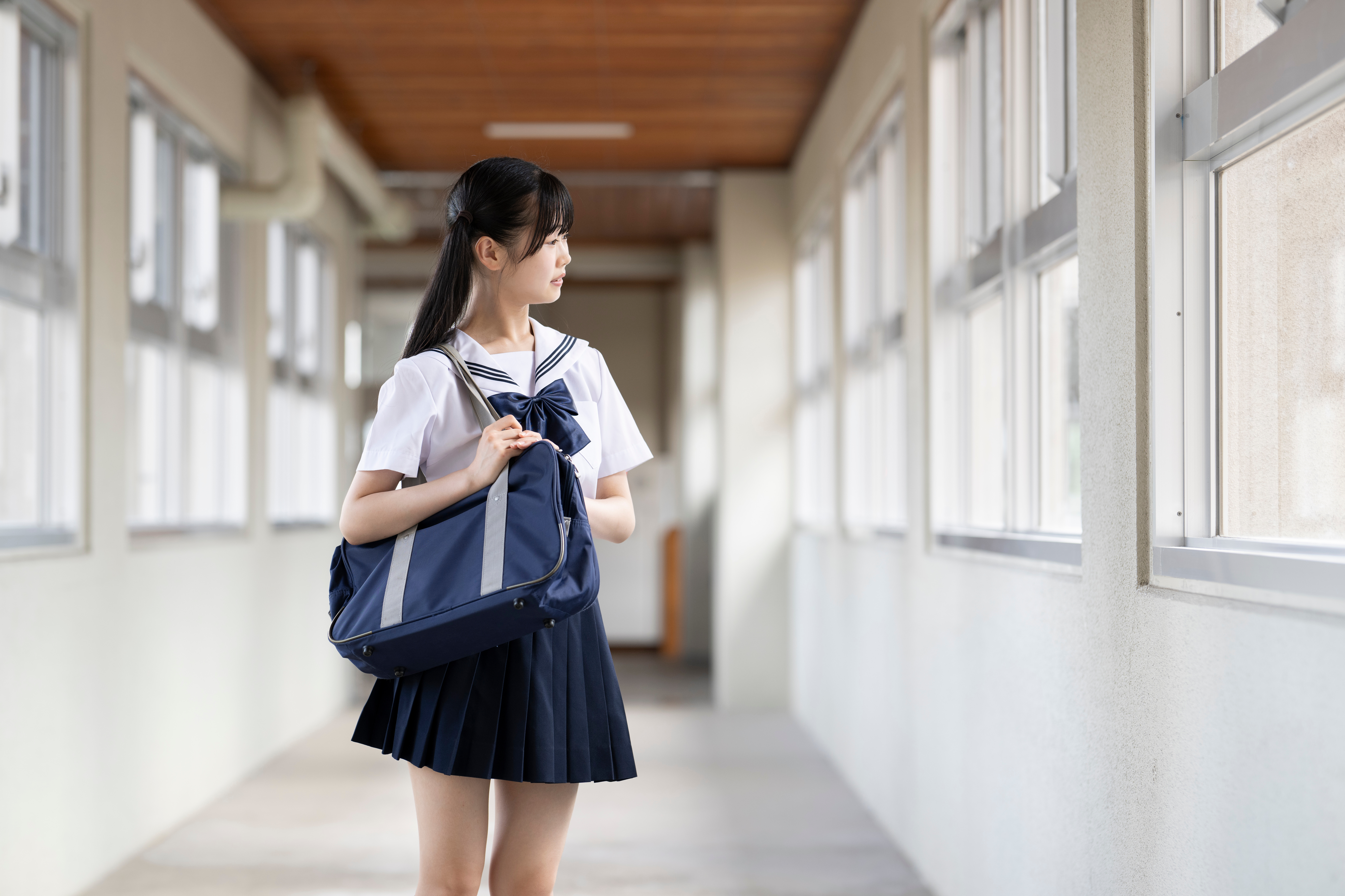 学校の廊下で外を見ている女子高生