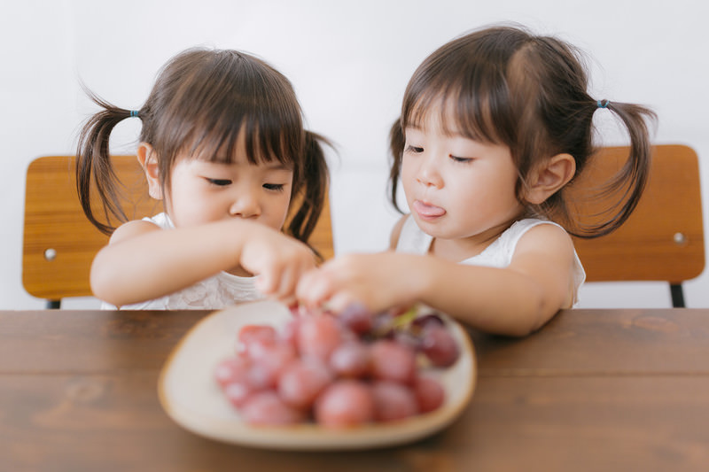 二人の女の子がフルーツを食べている写真