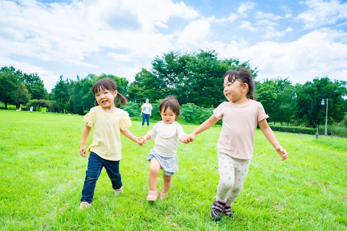 3人の子どもが手を繋いで遊ぶ様子。