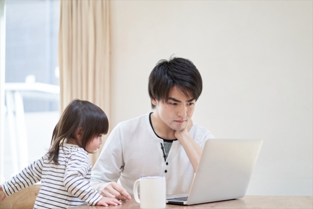 お父さんと女の子がパソコンを見ている写真