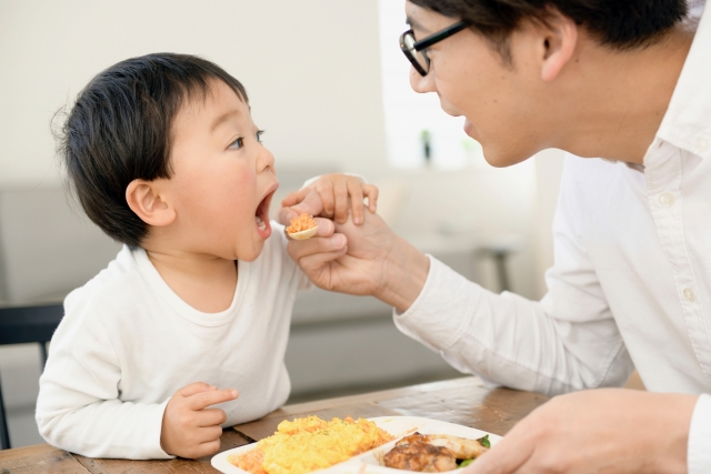 お父さんが子供にご飯をあげている写真