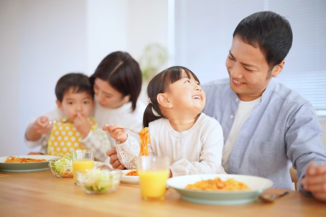 両親が子供にご飯を食べさせている写真